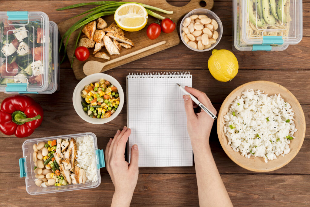 hands-writing-notebook-with-casseroles-ad-food