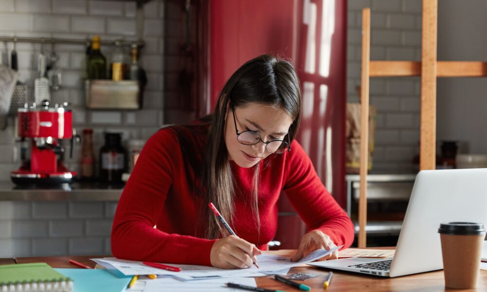 7 Smart Money Habits for a Secure Future Person calculating expenses and planning savings with coins and a notebook