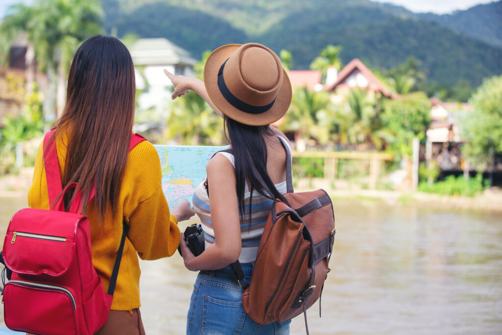 two-female-tourists-hold-map-find-places 