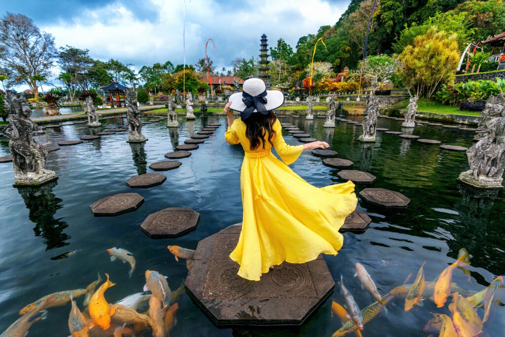 woman-standing-pond-with-colorful-fish-tirta-gangga-water-palace-bali-indonesia 
