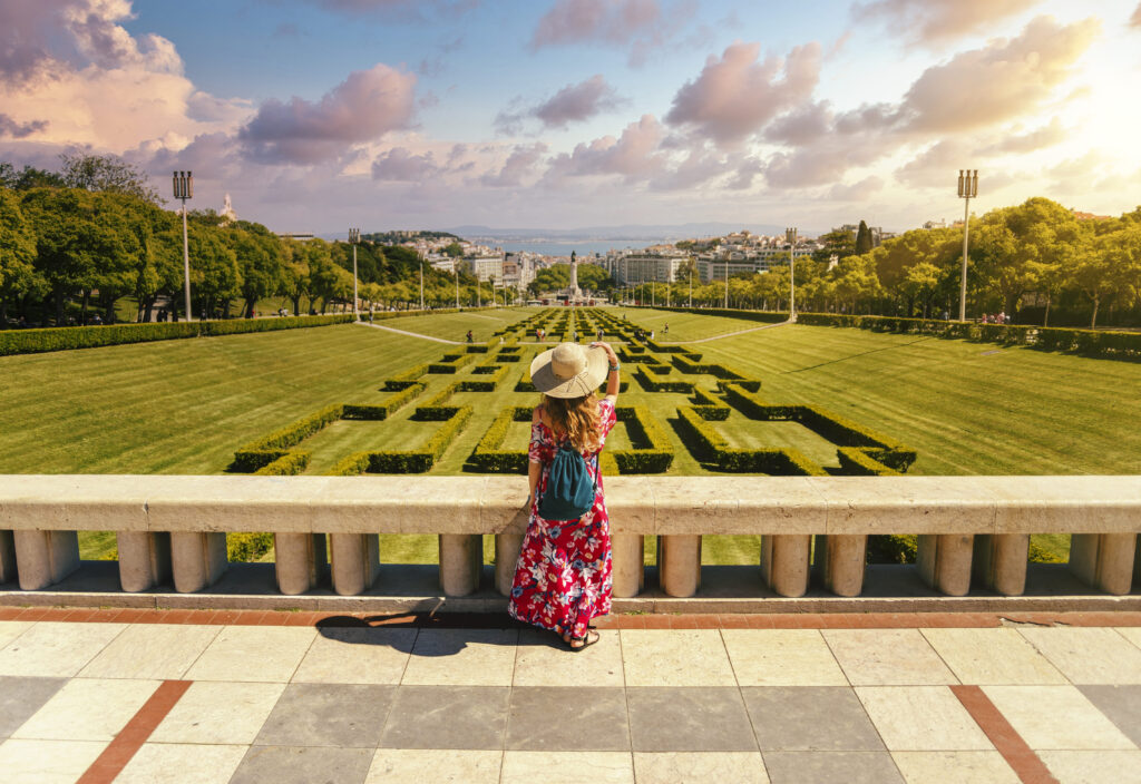 young-female-tourist-red-floral-dress-eduardo-vii-park-sunlight-portugal 