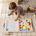 A collection of simple, screen-free kids activities like playdough, books, and building blocks laid out on a wooden floor.