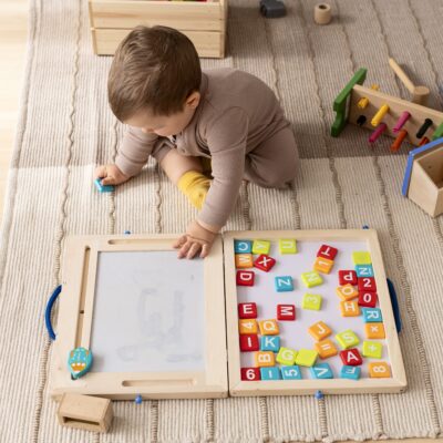 A collection of simple, screen-free kids activities like playdough, books, and building blocks laid out on a wooden floor.