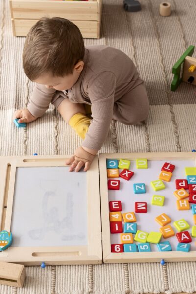 A collection of simple, screen-free kids activities like playdough, books, and building blocks laid out on a wooden floor.