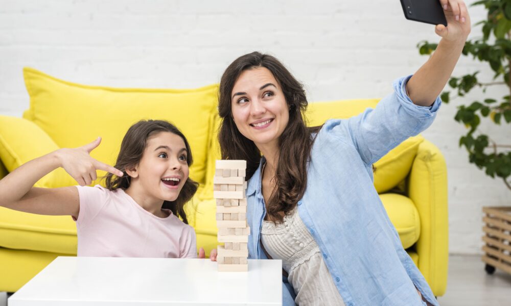 The 10-Minute Miracle: How This Simple Habit Transformed My Chaotic Home A tired but happy mother and daughter laughing together while building a block tower on the living room floor.